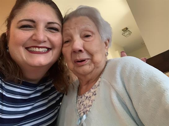Two women share a warm smile during a heartfelt visit in a cozy living room.
