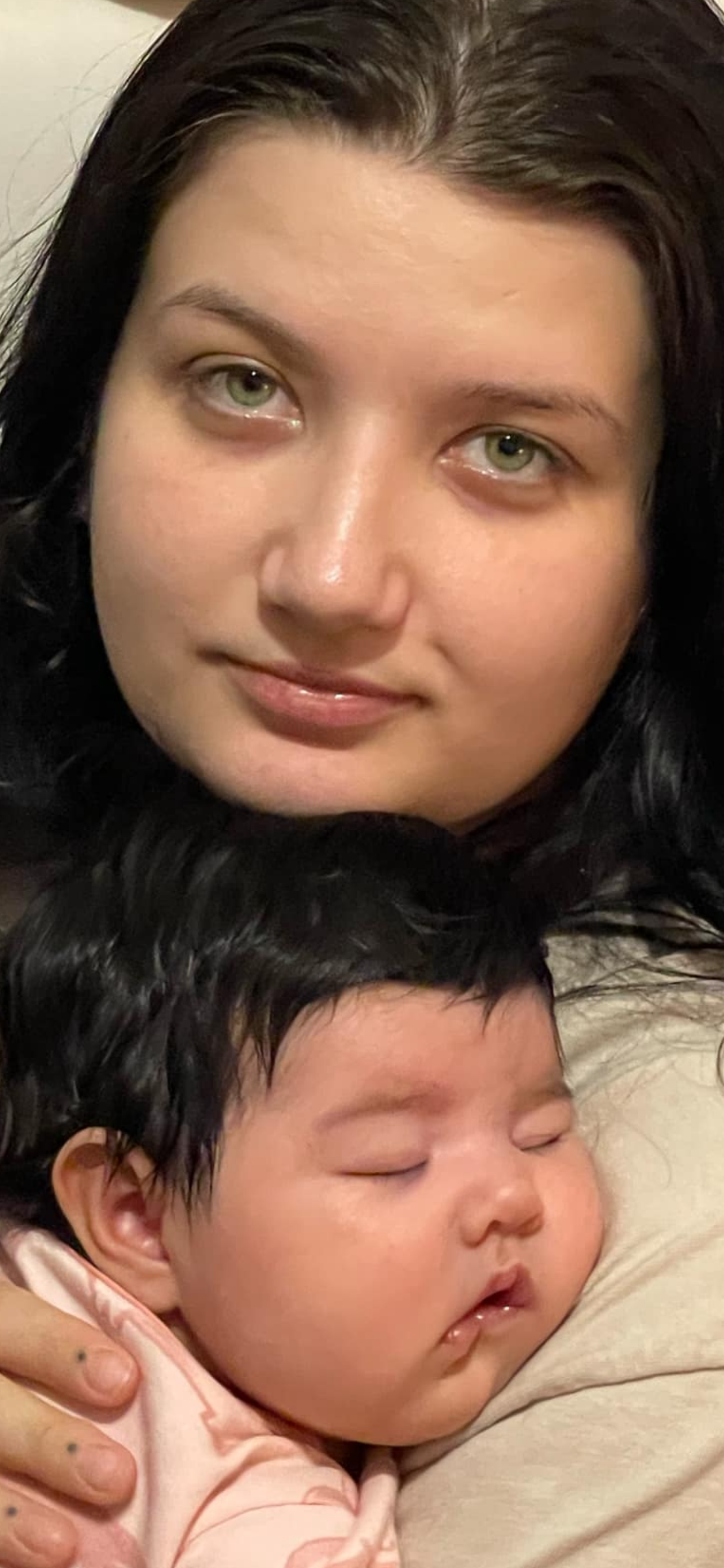 A woman enjoys a quiet moment with her sleeping baby in her arms at home.