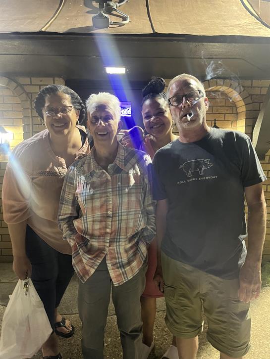 Four family members enjoy a joyful moment outside a restaurant at night, laughing and posing.