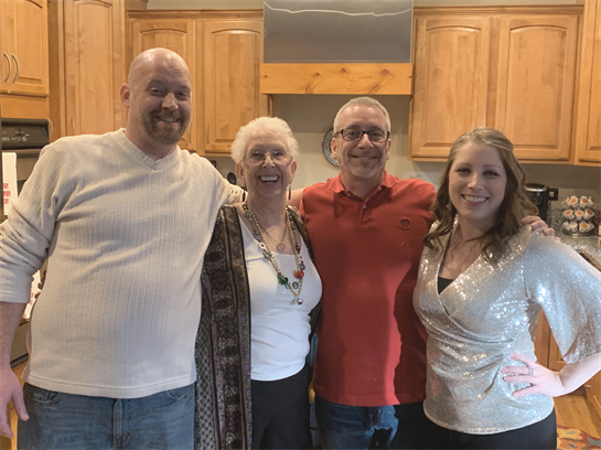 Four family members pose happily in a cozy kitchen, enjoying a special moment together.