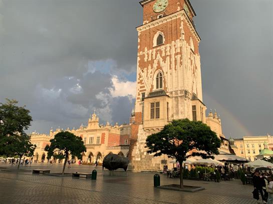 A vibrant evening in Krakow features a rainbow arching over historical buildings after rain.