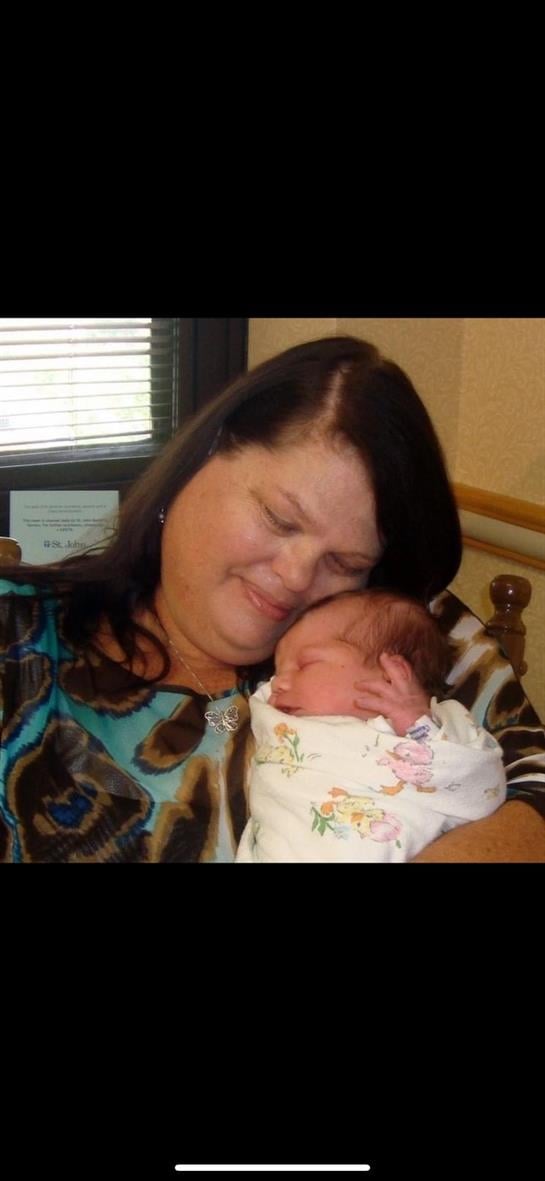A grandmother lovingly holds her newborn granddaughter, radiating warmth and happiness.