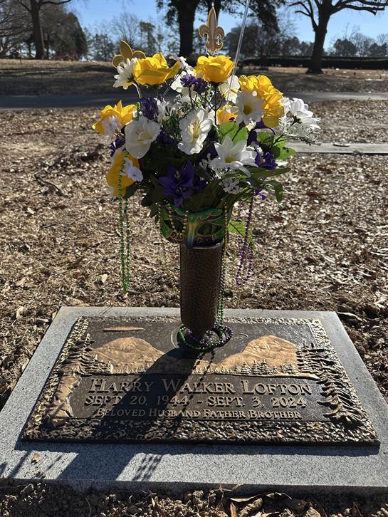 A colorful flower bouquet honors Harry Walker Lofton at his grave in a peaceful cemetery.