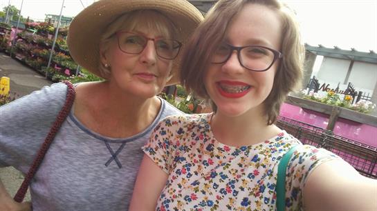 Two women enjoy a cheerful moment while shopping for plants in a vibrant garden center.