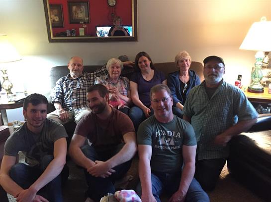 A warm family gathering featuring multiple generations sitting together in a cozy living room.