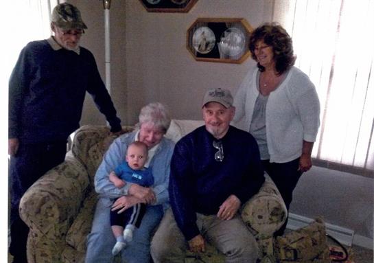 Family enjoying time together in a cozy living room with a child and grandparents present.
