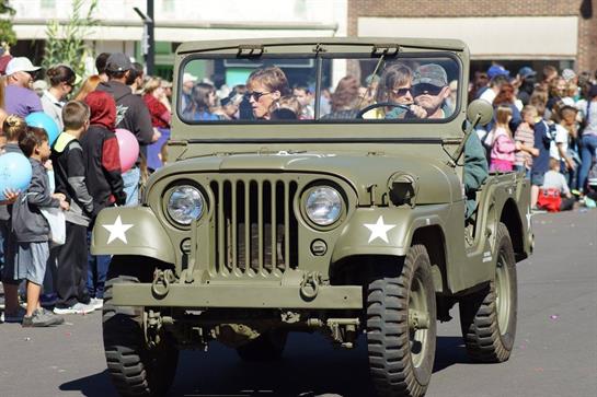 A green military vehicle with people in the back