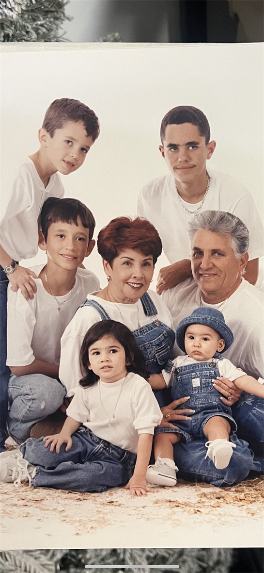 Family smiles together as grandparents hold grandkids in a bright indoor space.