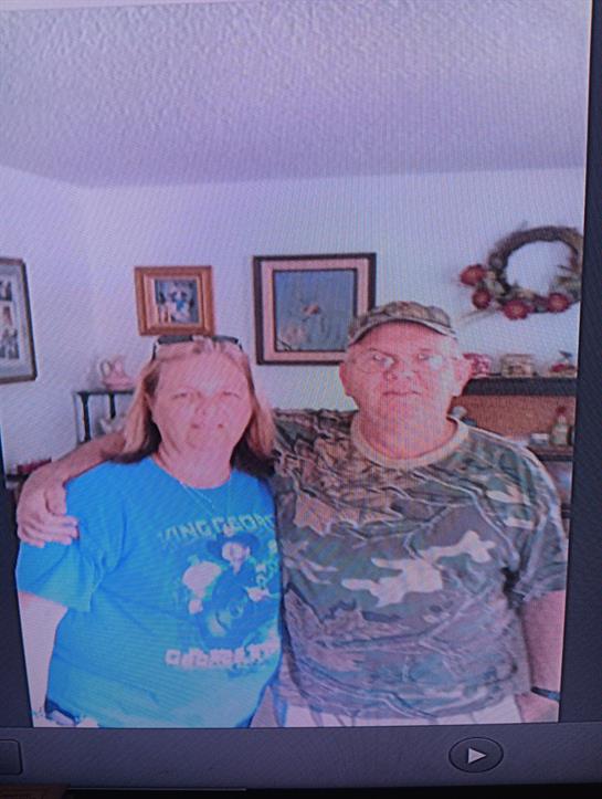 A cheerful couple stands close in a warmly decorated living room filled with personal touches.