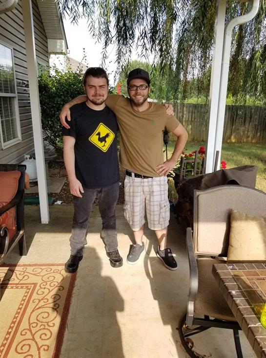 Friends enjoy a casual moment together on a porch surrounded by greenery and sunlight.