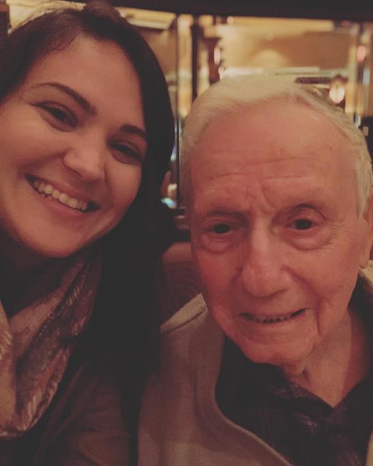 A joyful moment shared as a woman and an elderly man smile for a selfie while dining out.