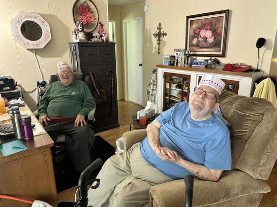 Two elderly men relax in a warm living room, enjoying each other's conversation.