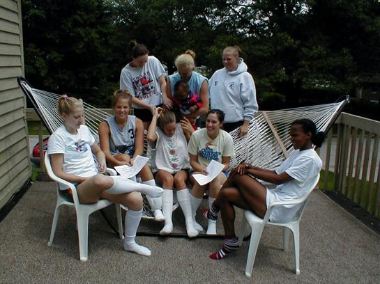 A lively group enjoys each other's company on a porch, sharing stories and laughter on a sunny day.