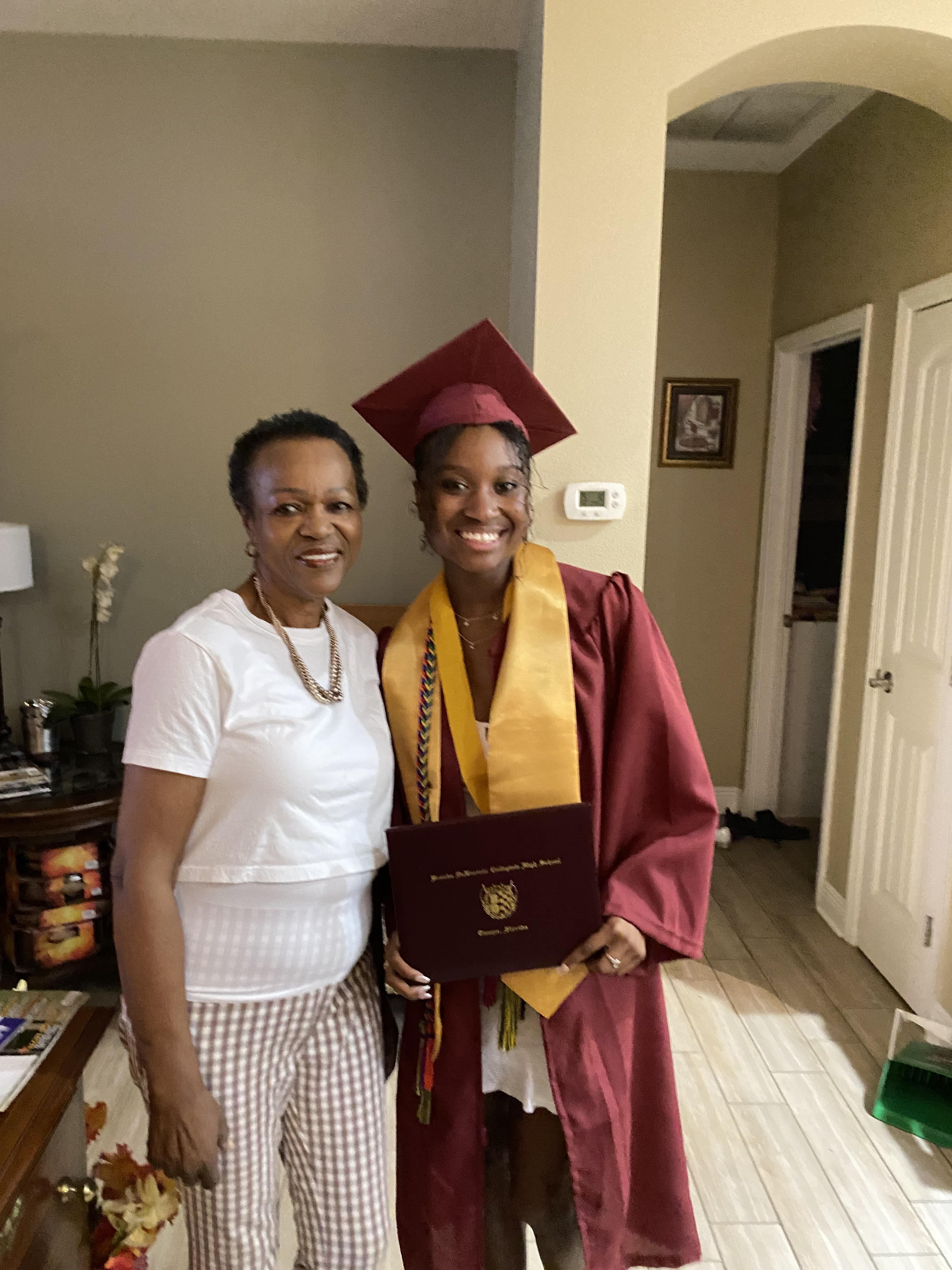 Graduates and family members share a joyful moment in a living room after a graduation ceremony.