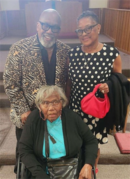 Three adults pose happily together in a church setting with a welcoming ambiance.