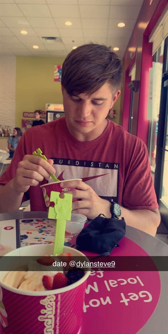A young man is focused on his dessert while sharing a casual date in a colorful cafe.