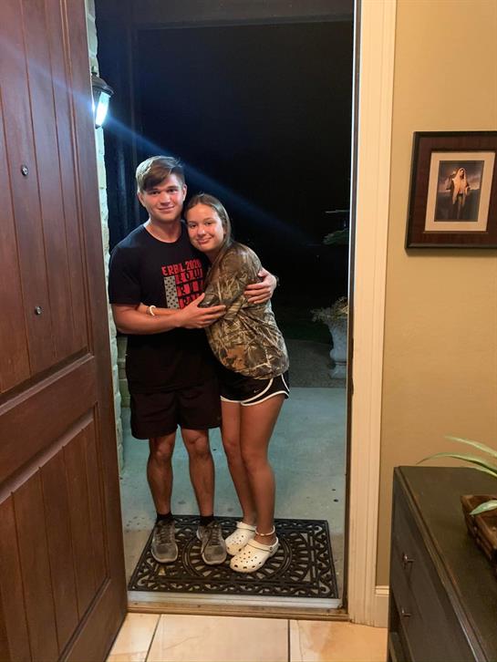 A cheerful couple stands close together at the open entrance, enjoying a warm evening.