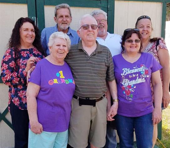 Smiling family members pose together outdoors, enjoying a joyful reunion in the sun.