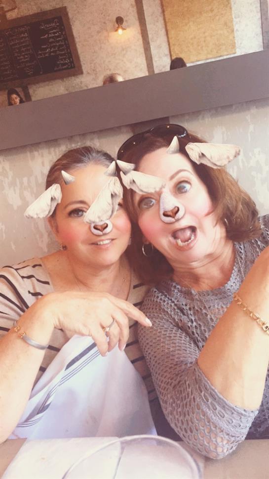 Friends share laughter and joy while using playful animal filters in a casual cafe setting.
