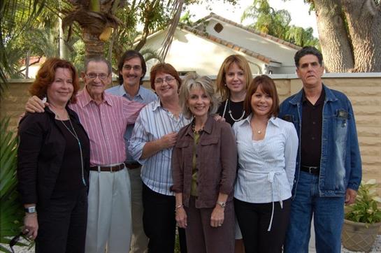 Group of eight family members gathered outdoors, sharing laughter and warm conversations together.