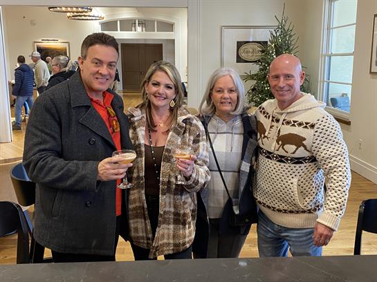 Four friends toast with drinks in a warm, festive atmosphere, enjoying winter cheer.