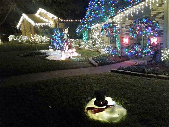 Colorful holiday lights brighten homes and yards, creating a festive nighttime atmosphere.