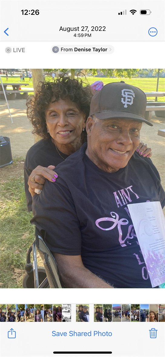 A couple relaxes in a park, smiling and sharing a moment together with food and drinks nearby.
