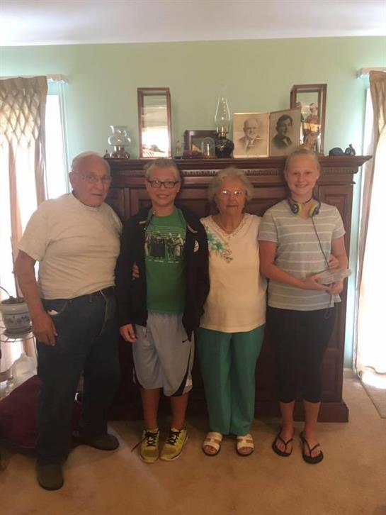 Four family members gather together in a warm living room, smiling happily during summer.