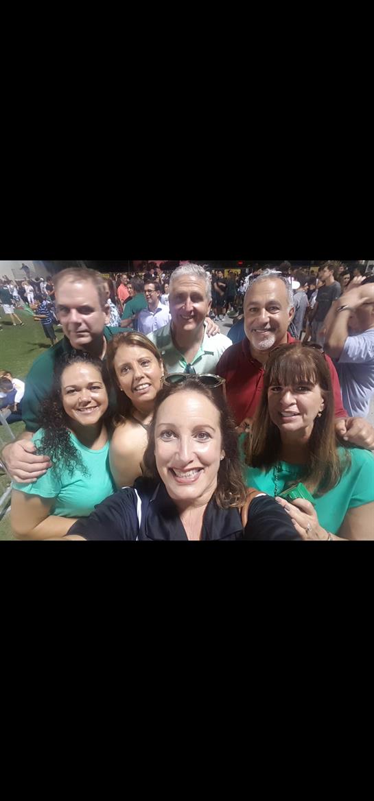 People stand together, smiling and posing happily at a vibrant outdoor gathering.