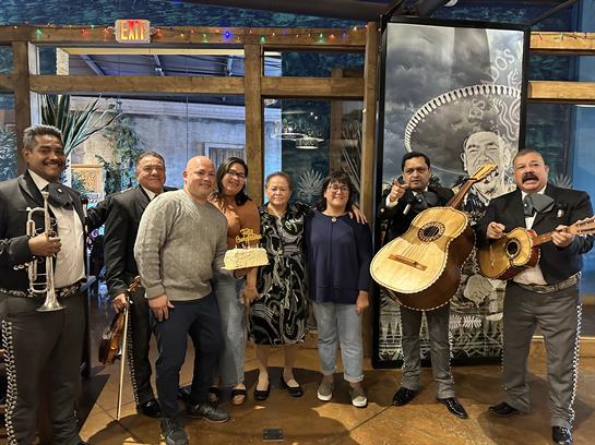Friends enjoy a festive moment with a mariachi band while celebrating a meaningful occasion.
