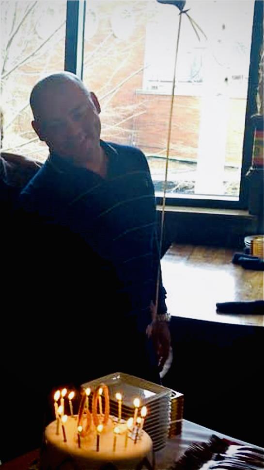 A group enjoys a birthday celebration with candles and laughter in a warm, inviting cafe.