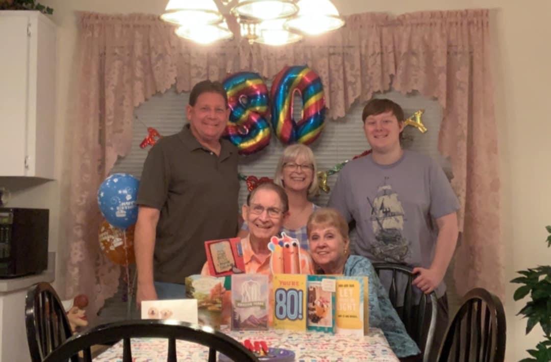 Family members gather around a table decorated for a milestone birthday celebration.