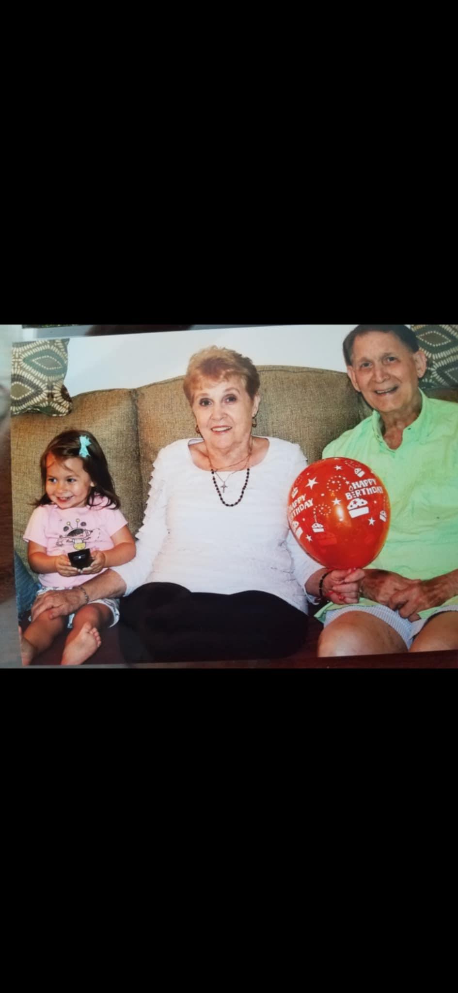 A joyful moment shared by three family members sitting on a couch, with balloons and smiles.