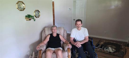 Two individuals sit comfortably in a well-lit living room, sharing a joyful moment.