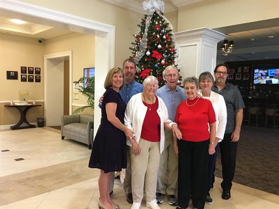 A happy family gathers by a decorated Christmas tree, celebrating the holiday season.