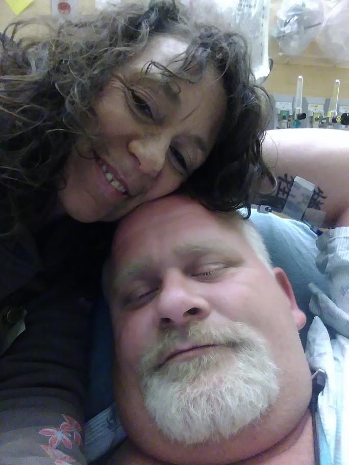 A man and woman embrace in a hospital, sharing a heartfelt moment of affection.