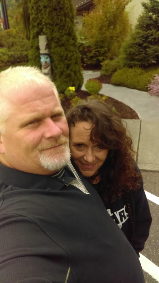 A couple shares a moment together outdoors in a beautifully landscaped area amid blooming flowers.