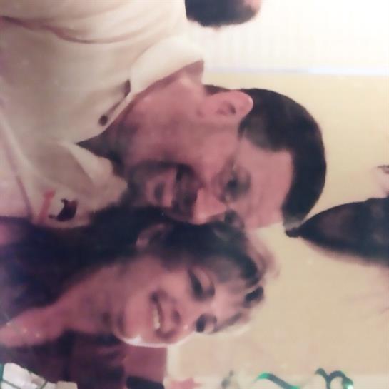 A cheerful couple shares laughter during a social event, surrounded by friends in a cozy atmosphere.