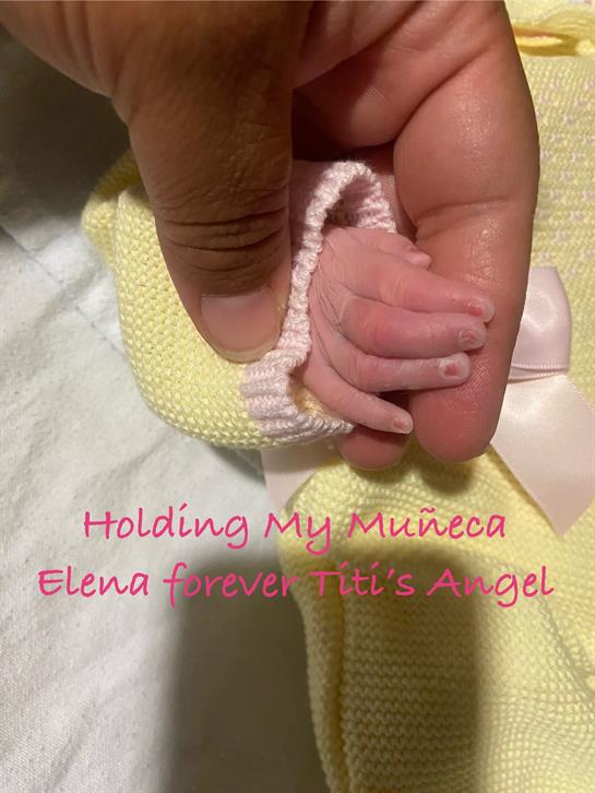 A person gently holds a newborn's tiny hand in a cozy setting, showcasing love and connection.