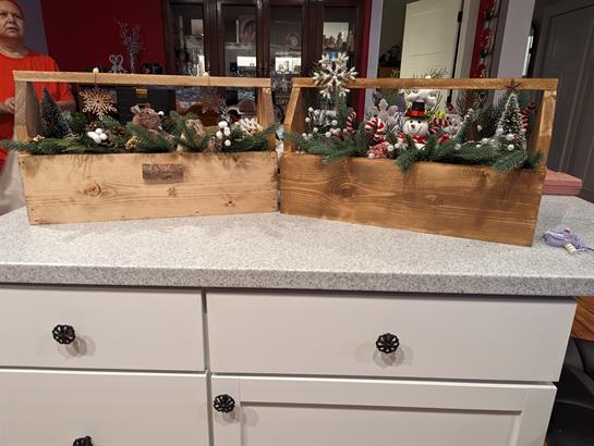 Two charming wooden boxes brimming with decor sit on a kitchen countertop, adding a festive touch.