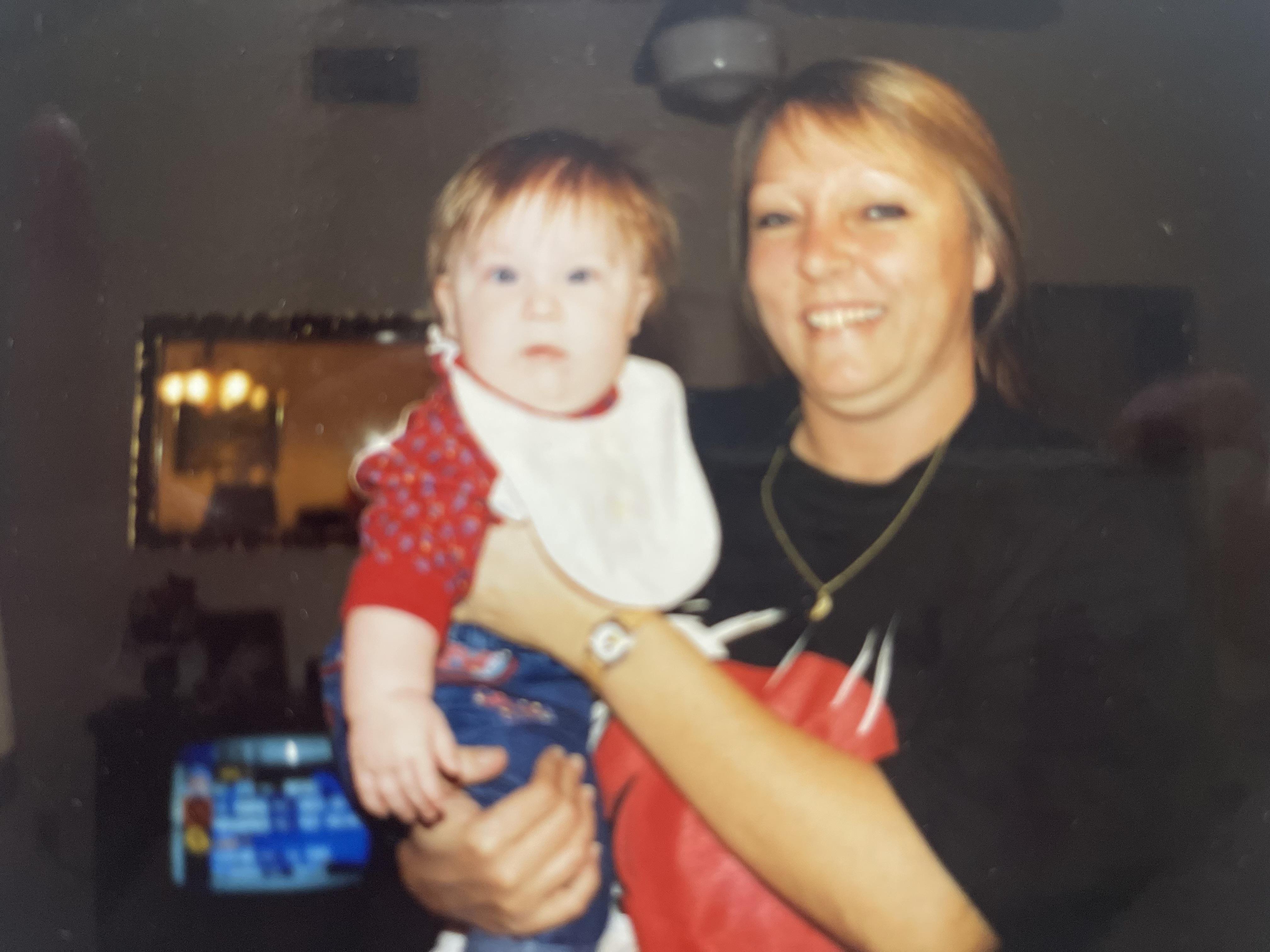 A woman joyfully holds a baby while smiling in a warm and inviting living room setting.