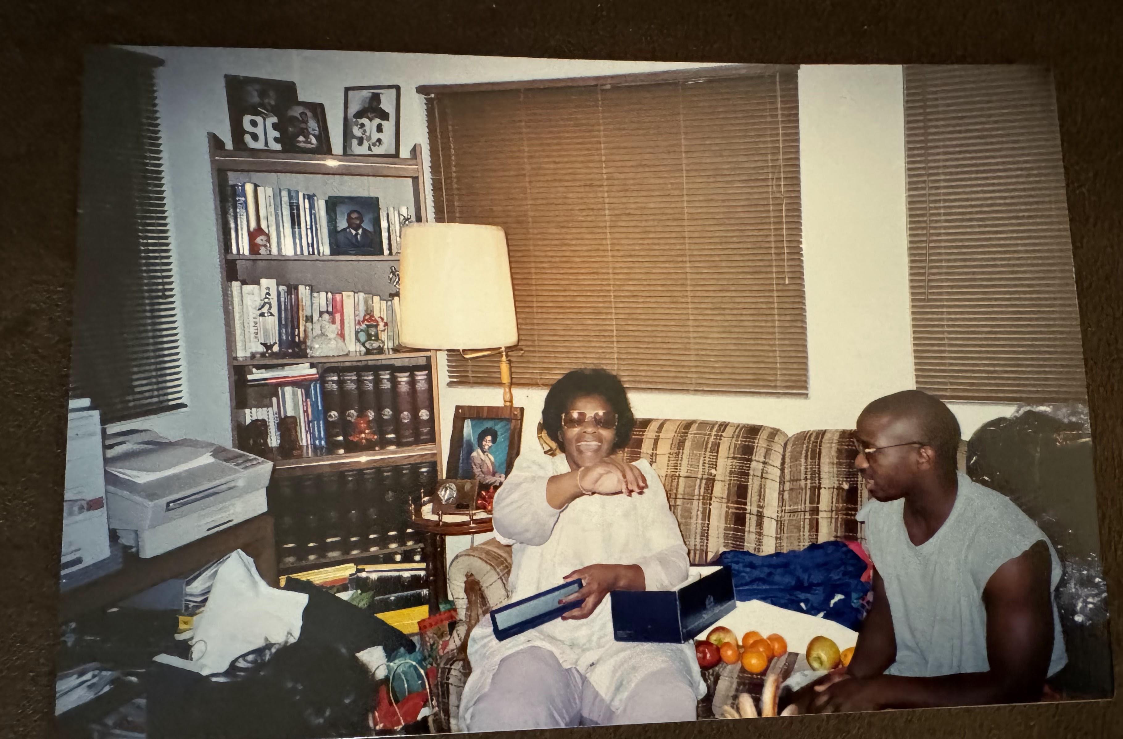 Two friends enjoy a casual conversation in a warm living room filled with books and snacks.