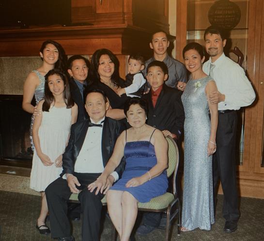 A large family poses together at an indoor event, dressed in formal attire and smiling.