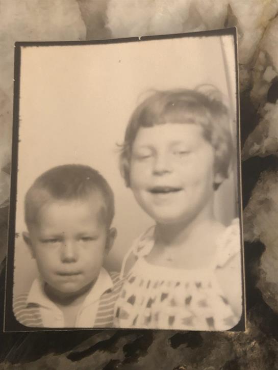 Siblings smile for a portrait, showcasing their playful expressions and nostalgic attire.