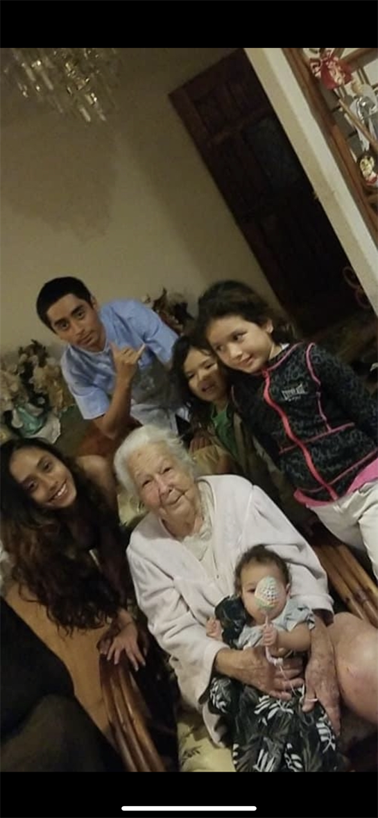 A warm family gathering shows three young children, their parents, and a grandmother, smiling.