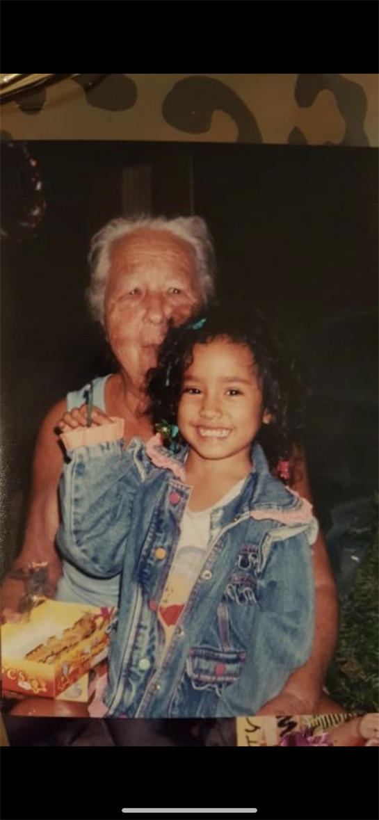 A joyful girl poses with her grandmother, both smiling as they celebrate together with a cake.
