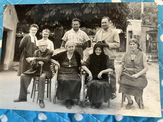 A gathering of family members in traditional attire, celebrating together in a rural area.