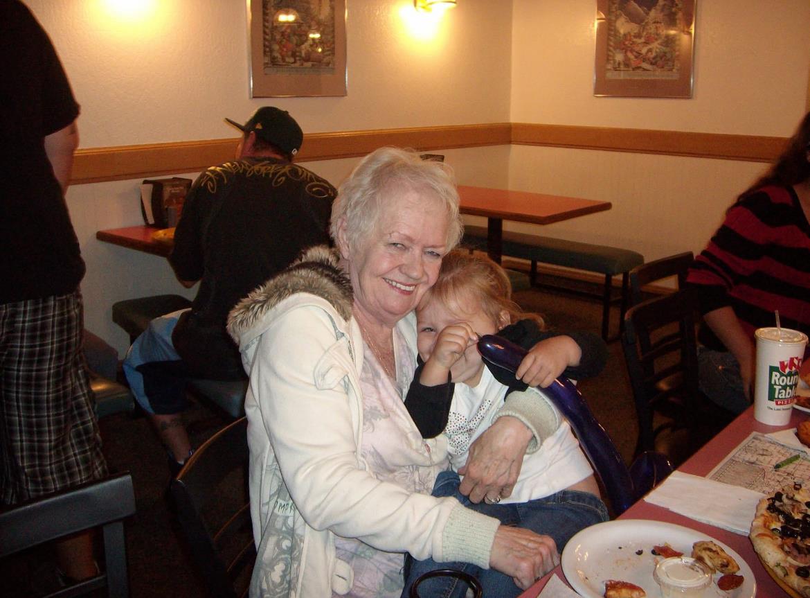 A grandmother embraces her young grandchild warmly while enjoying a meal in a cafe.