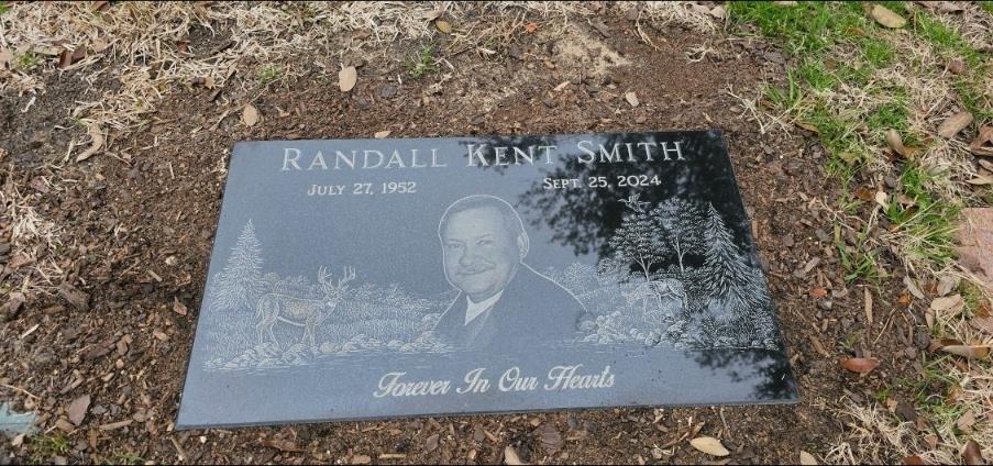 A memorial stone honors Randall Kent Smith, engraved with nature scenes and a warm sentiment.