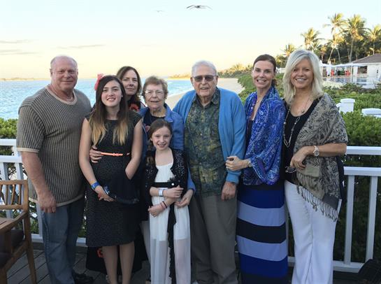 A family of eight poses happily together by the beach at sunset, celebrating moments of joy.